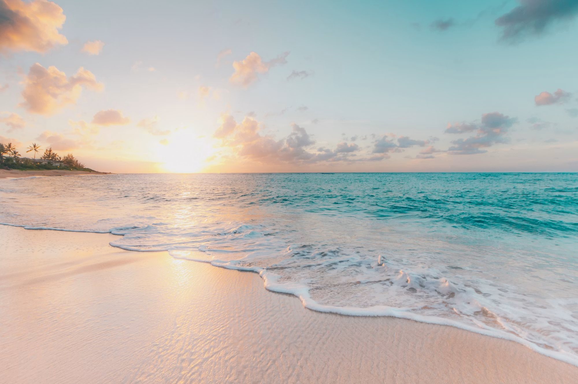 Plage de sable clair et eau turquoise au soleil couchant